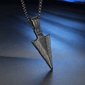 Macro shot of black stainless steel arrow pendant with textured surface and chain