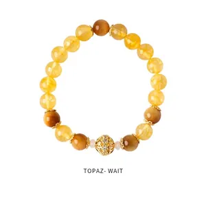 Detail of citrine beaded bracelet featuring a hollow golden floral charm with rhinestones