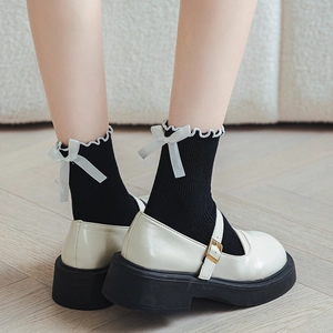 Detail of black frilly socks with white bows paired with cream Mary Jane platform shoes