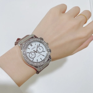 Detail showing a white dial quartz watch with crystal bezel and brown leather strap