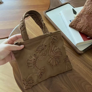 Detailed close-up of vintage brown suede tote bag featuring intricate floral embroidery