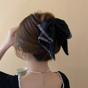 Detail of large black satin bow hair claw with rhinestones on a brunette hairstyle
