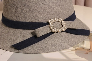 Détail d'un chapeau cloche en laine avec boucle en cristal sur ruban de velours bleu