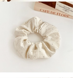 Detail of cream fabric scrunchie with rhinestones on a vintage book background