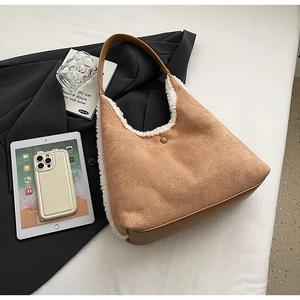 Detail of a brown faux suede shoulder bag with white faux fur trim on a black blazer