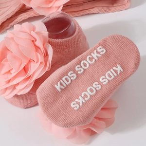 Chaussettes bébé roses en coton tricoté avec fleurs et semelles antidérapantes sur blanc