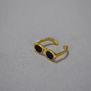 Macro shot of unique gold sunglasses-shaped ring on grey fabric, showcasing detail