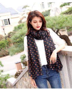 Close-up of lightweight black chiffon scarf with orange polka dots worn by a model