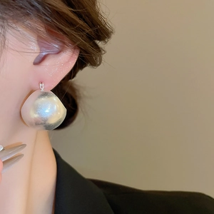 Close-up of large U-shaped dome earrings with pearlescent finish on model