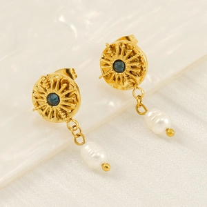 Detailed close-up of gold starburst earrings with blue gemstone and irregular pearls