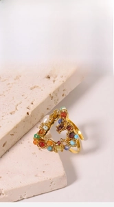 Macro detail of heart-shaped gold ring with colorful beads on a natural stone background