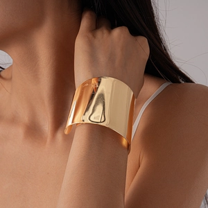 Bracelet manchette large doré à finition miroir géométrique sur le poignet d'un mannequin