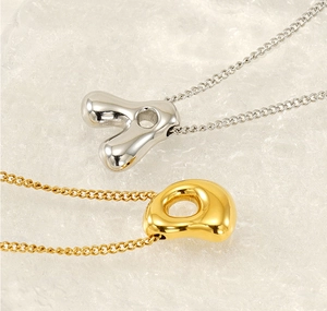 Close-up of gold and silver bubble letter necklaces with smooth polished finish