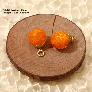 Macro shot of orange-shaped glass pendants with realistic texture and 13x19mm size label
