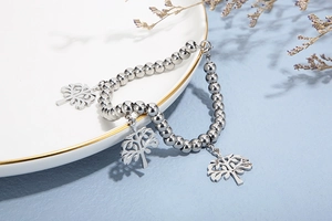 Gros plan détaillé du bracelet à perles avec charms arbre de vie sur fond marbre