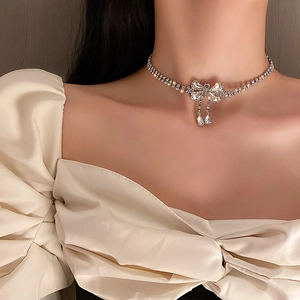 Silver bow choker necklace with sparkling rhinestones and teardrop pendants on model