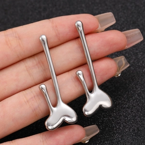 Detail of silver polished liquid metal earrings with heart shape and long linear post