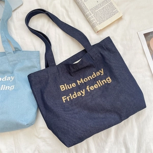Dettaglio di borse tote in denim con ricamo giallo su tessuto bianco strutturato elegante