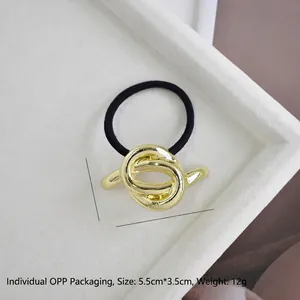 Close-up of golden alloy hair tie with measurement 5.5cm by 3.5cm in a white tray