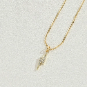 Close-up of gold lightning bolt pendant with sparkling crystals on thin chain