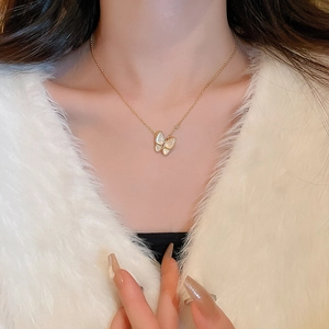 Dettaglio di elegante collana a farfalla dorata con intarsio in madreperla su modella