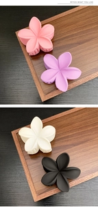 Detailed view of matte flower hair claws in pink, purple, white, and black colors