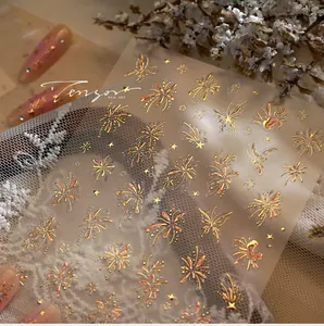 Macro shot of gold laser butterfly and firework nail stickers on a lace background