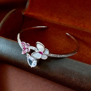 Macro detail of silver-tone butterfly cuff with white shell and purple zircon accents