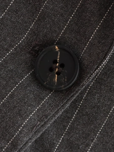 Detailed macro view of dark gray pinstripe vest fabric with high quality resin button