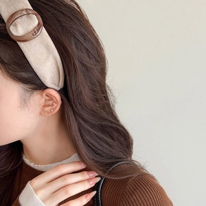 Detail of beige fabric headband featuring a brown tortoiseshell resin ring buckle accessory