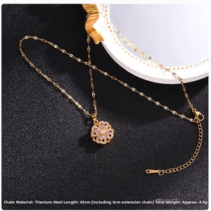 Detailed macro of gold clover necklace with pink zircons on black matte surface