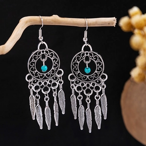Macro shot of silver bohemian dreamcatcher earrings with turquoise beads and metal feathers