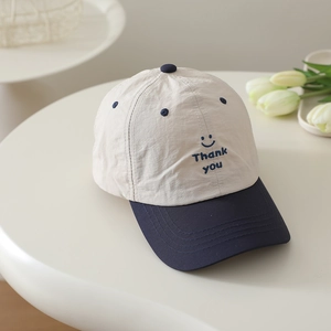 Detail view of the smile and Thank You embroidery on this beige baseball cap