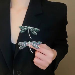 Elegante libellenbroche met groene en paarse zirkonia op een zwart colbertjasje