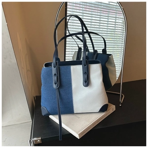 Detailed close-up of denim blue and beige canvas tote bag with leather strap handles