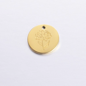 Detailed view of a golden circular pendant with engraved birthday flower pattern on white