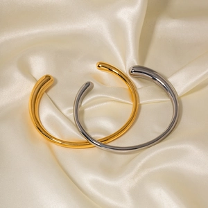 Polished gold and silver stainless steel open cuff bangles with teardrop ends on silk