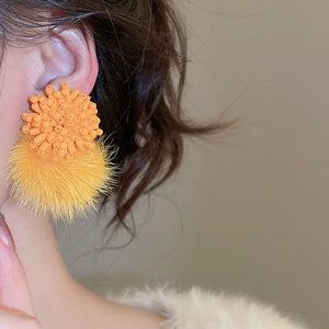 Close-up of model wearing orange handmade beaded floral and plush ball drop earrings