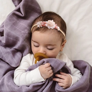 Detailed view of pink floral baby headband with pearls on a sleeping infant