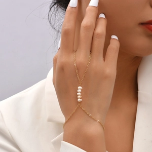 Elegant gold chain bracelet with five white pearls worn on a model's hand for a simple look