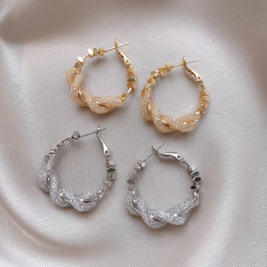 Detailed view of intertwined twisted metal hoop earrings in gold and silver finishes