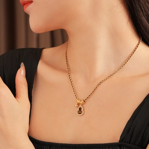Detail shot of a gourd tiger eye pendant necklace with zircon on a gold and black chain