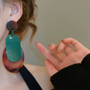 Gros plan de boucles d'oreilles géométriques en acrylique avec motifs écaillés et fini brillant