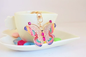 Detail of a gold butterfly keychain with sparkling rhinestones and colorful enamel inlay