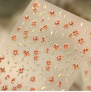 Macro detail of floral nail stickers with 3D gold leaves and white pearl accents