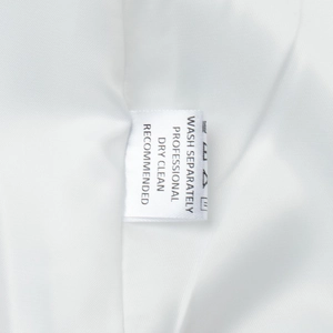 Close-up of garment care label with professional dry clean instructions on white fabric
