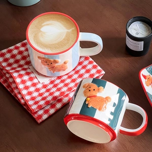 Detail of ceramic coffee mugs with hand-painted dog relief on red and white checkered cloth
