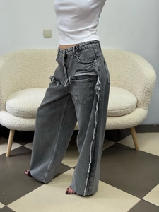 Detail of dark grey distressed wide leg jeans showing raw frayed edges and side pockets