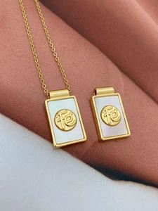 Close-up of gold rectangular mother of pearl pendants with Fe faith relief engraving