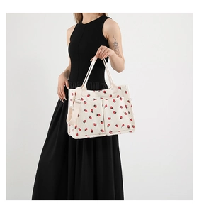Close-up of strawberry print corduroy tote bag with large front pockets and long strap
